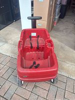 Front view of red plastic wagon showing seat belts and cup holder