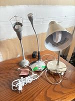 Three silver gooseneck desk lamps on wooden surface showing overall lot