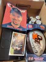Top view of box showing signed BC Lions football in Wilson box, Wally Buono signed card, Daniel Negreanu signed magazine cover, miniature trophies