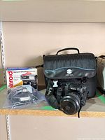 Lot overview showing Sony camera, Minolta bag, Polaroid box, bag of accessories