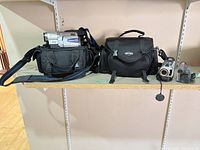 Sony camcorder with two carrying bags on shelf