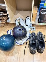 Two bowling balls, Dexter shoes, drawstring bag and towel on floor