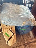 Blue and white mattress overlay in clear plastic plus beige carry bag