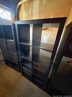 Front view of black Ikea Kallax shelving unit with cubbies and accessories