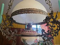 Overall view showing milk-glass dome, ornate brass arms and candle holders