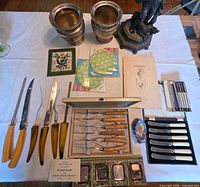 Overview of entire lot including goblets, carving set, boxes of knives, dishes, plates, napkins, trivet and card