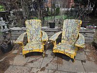 Front view of both yellow splatter-painted Adirondack chairs on patio