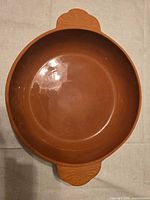 Top view of round terracotta cazuela showing glazed interior and two handles