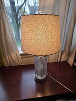 Full view lit lamp showing shade, glass column, base