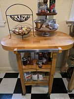 Full view of wood kitchen cart showing butcher block top, metal towel bar, lower shelf, drawers, wire basket, casters