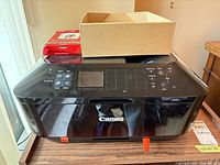 Front view of Canon MX922 printer with ink cartridges and photo paper on top