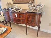 Full view of serpentine mahogany sideboard with drawers, cabinet doors, brass pulls, and inlay