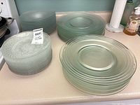 Stacks of seafoam dinner plates, frosted plates and textured clear plates on countertop