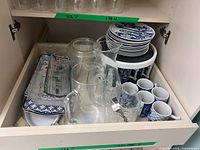 Drawer with clear glass pitchers, plates, trays and mugs