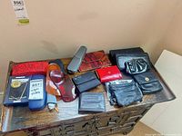 Full lot overview on tabletop showing all wallets, pouches, cases, lenses and handbag hook