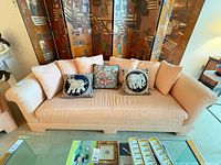 Front view of peach 3-seater sofa with five throw pillows