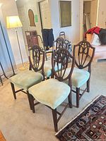 Front view of four Hepplewhite chairs showing upholstery and frames