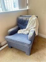 Front view of blue patterned armchair with blanket