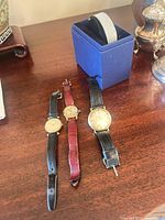 Overview of three gold-tone wristwatches and Swarovski bracelet in box on table