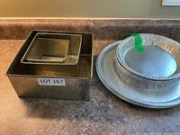 Nested square fruitcake pans beside stack of round platters and foil pans