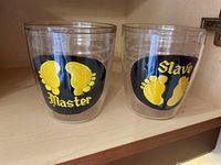 Two clear plastic tumblers with yellow footprints decals and text