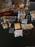 Overview of assorted bead vials, jars, bags of findings spread on table