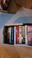 Box of assorted books with spines showing visible titles