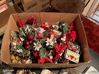 Box containing artificial holly and poinsettia picks, gold garland, assorted small packaged ornaments