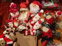 Group of plush Christmas characters in box: snowman, Santa heads, plush frogs, mice, teddy bear, elves