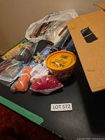 Overview of assorted craft supplies on table with box and lot tag