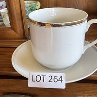 Oversized white porcelain cup with gold rim resting on matching plate