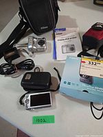 Lot overview showing both cameras, cases, charger, manuals, Canon box