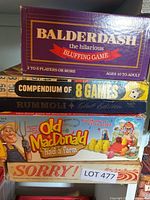 Stack of five boxed board games: Balderdash, Compendium of 8 Games, Rummoli, Old MacDonald Had a Farm, Sorry!