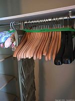 Wood, black plastic, and satin padded hangers on closet rod