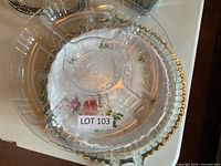 Clear glass divided tray stacked over floral porcelain dish and handled glass platter