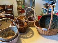 Group of assorted baskets on tabletop showing variety of colours, sizes and handles