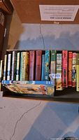 Open box showing full row of assorted vintage hardcovers with one book laid on top