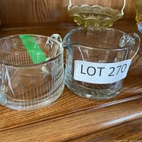 Two clear glass spouted cups, one with handle and one without
