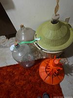 Overall view: two glass carboys, demijohn in basket, orange bottle drying rack