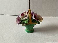 Front view of bone china basket showing green base, gold handle, multicolour flowers
