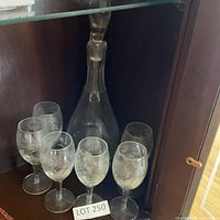 Carafe and six glasses displayed together in cabinet