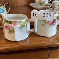 Cream pitcher and sugar bowl with floral design displayed on wooden surface