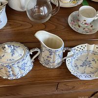 Cream pitcher, sugar bowl with lid, candy dish on wooden surface