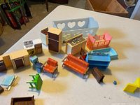 Assorted plastic dollhouse furniture pieces spread on table