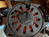 Top view of black plastic cord reel loaded with orange extension cord