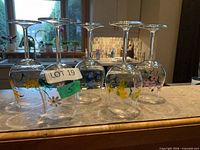 Six clear stemmed wine glasses inverted to display assorted hand-painted floral decorations