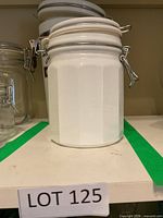 Faceted white ceramic canister with clamp lid on shelf