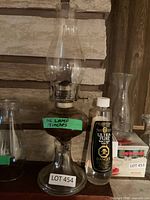 Glass oil lamp with chimney and bottle of lamp oil on shelf
