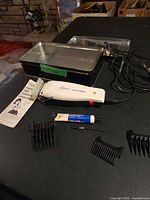 Full view of clipper, guards, grease tube, brush, tin