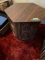 Overall view of one end table showing hexagonal top, carved doors
